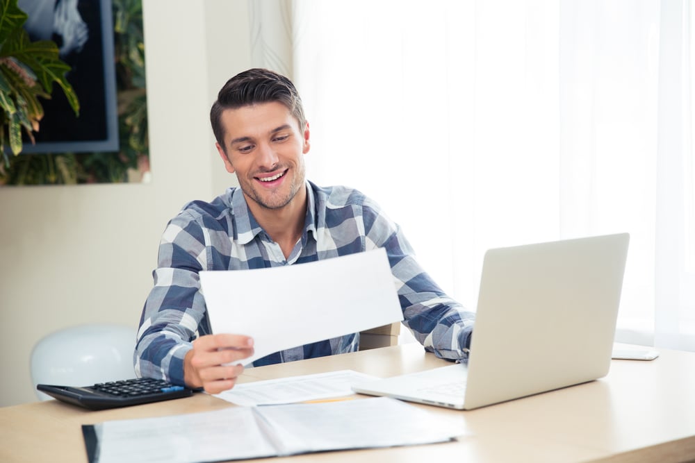 Portrait of a smiling man checking bills on the tablet at home