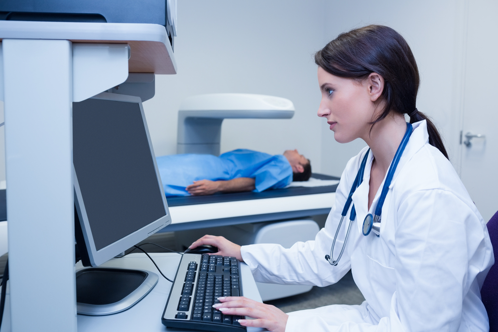 Doctor looking her computer while proceeding a radiography in hospital