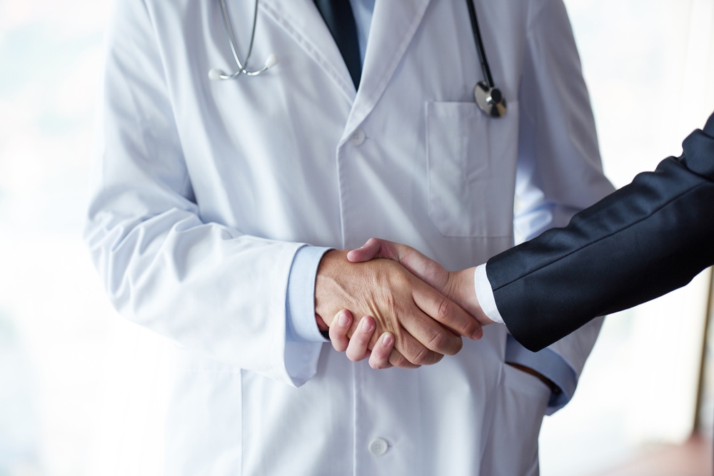 doctor handshake with a patient at doctors bright modern office in hospital